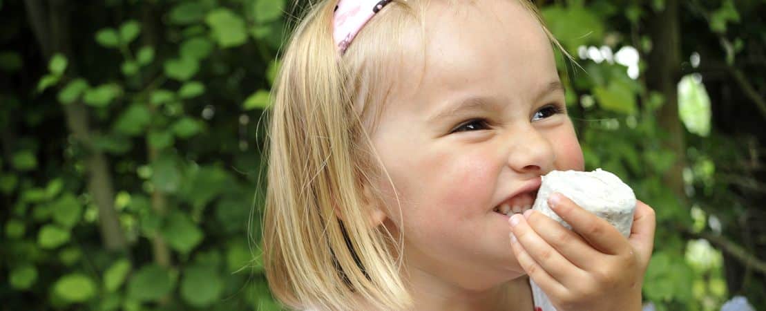 Petite fille qui mange un fromage de chèvre